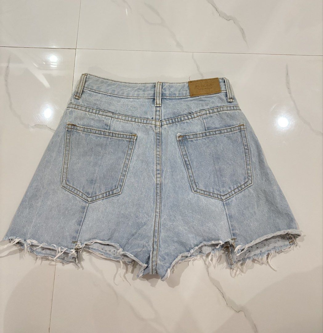 FANYI PURE light-wash denim shorts (Category: Skirts) located in San Fernando. Submitted by annecurates (Listing ID 1444761650, Image 3). Description: SIZE 26-27 faux-pearl embellishments gradients clustered along the frayed, raw hemline. The design includes front panel seams that create a slightly flared, flattering silhouette.