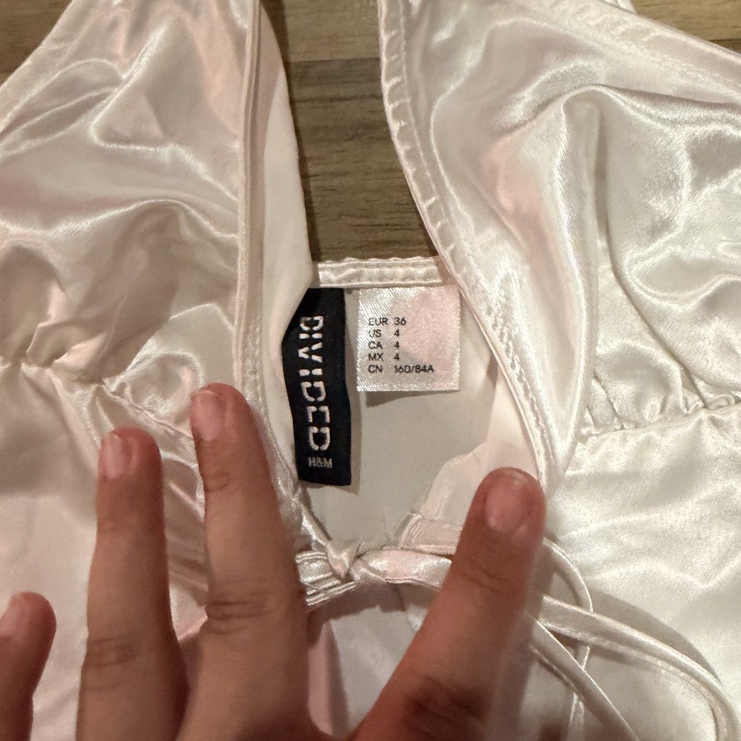 H&M White Satin Tie Front Crop Top (Category: Blouses) located in Pasig City. Submitted by katricem (Listing ID 1444804674, Image 2). Description: - White satin crop top from H&M - Features a tie front detail - Criss-cross straps at the back - Versatile: pairs well with jeans or skirts - Ideal for night outs or casual wear worn once super cute for party wear no pics when worn dm for manual measurement last price listed ‼️ items are all final sale