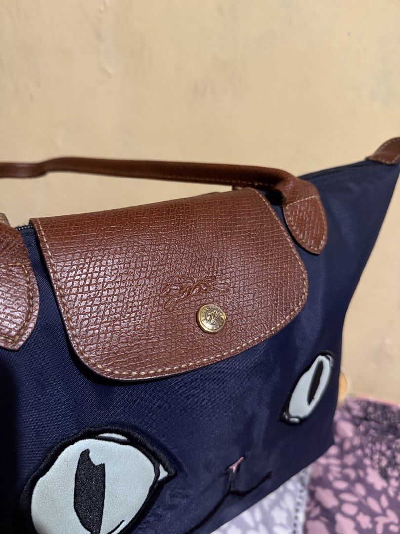 Longchamp Le Pliage Limited Edition Miaou (Category: Luxury Bags & Wallets) located in Caloocan City. Submitted by chnnnnns (Listing ID 1444827903, Image 3). Description: - Adorable navy blue tote bag - Features a cute cat face design on the front - Durable brown leather handles - Secure flap and zipper closure for the main compartment - Fun 'MIAOW' detail on the back - Ideal for everyday use or as a stylish accessory.