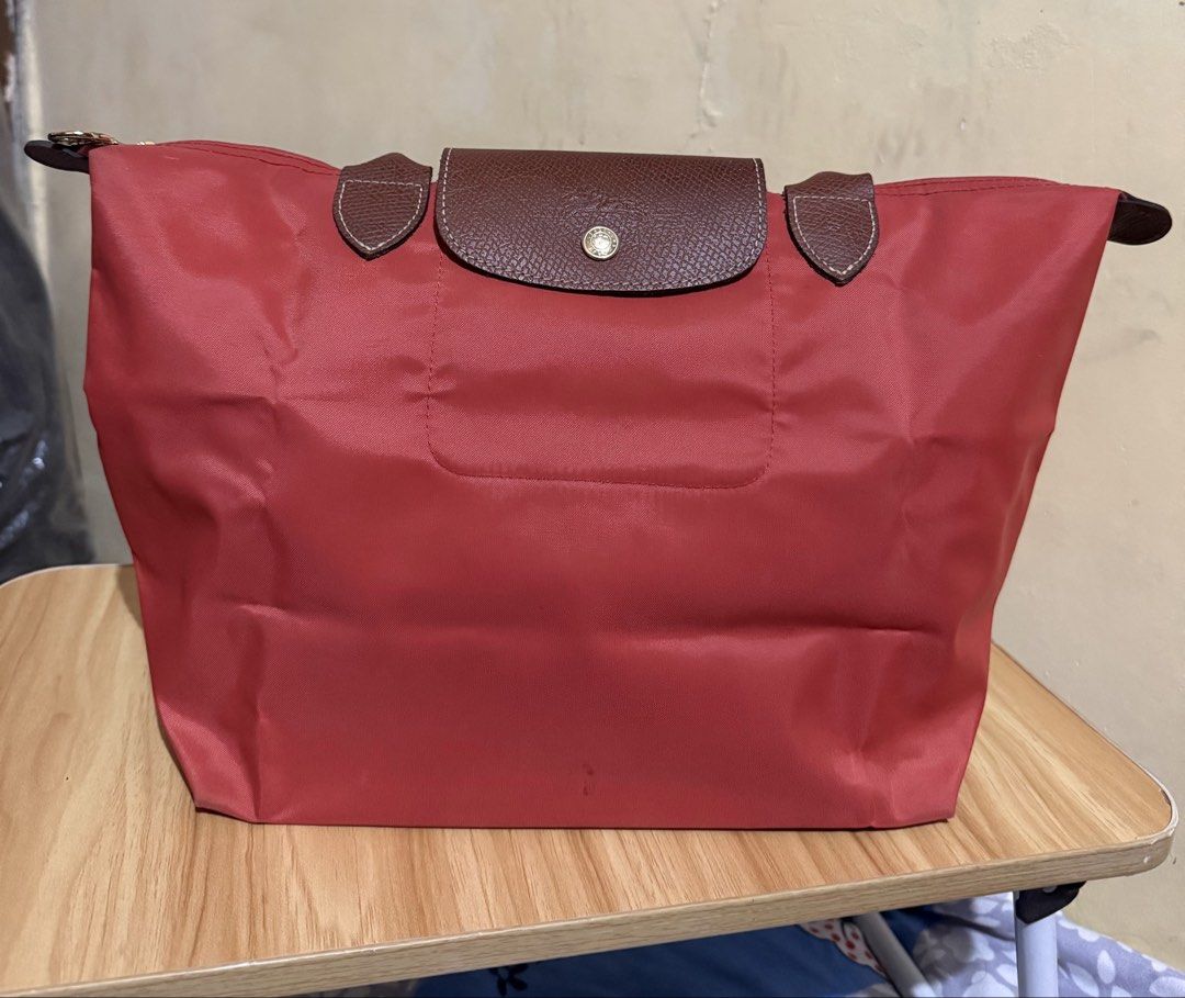 Longchamp Le Pliage Tote Bag - Tomato (Category: Luxury Bags & Wallets) located in Caloocan City. Submitted by chnnnnns (Listing ID 1444827706, Image 2). Description: - Classic Longchamp tote bag - Red nylon with brown leather handles and trim - Zips closed at the top - Ideal for everyday use - Spacious interior for essentials - Versatile and easy to carry.