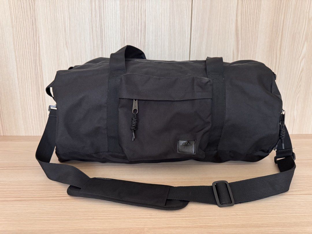 Steve Madden Black Duffel Bag with Shoulder Strap (Category: Shoulder Bags) located in Quezon City. Submitted by katharus (Listing ID 1444748188, Image 1). Description: - Stylish black duffel bag - Ideal for gym sessions or weekend getaways - Convenient front zippered pocket - Large main compartment for all your essentials - Includes a detachable shoulder strap for easy carrying - Dimensions: Approximately 20 inches long and 9 inches in diameter 