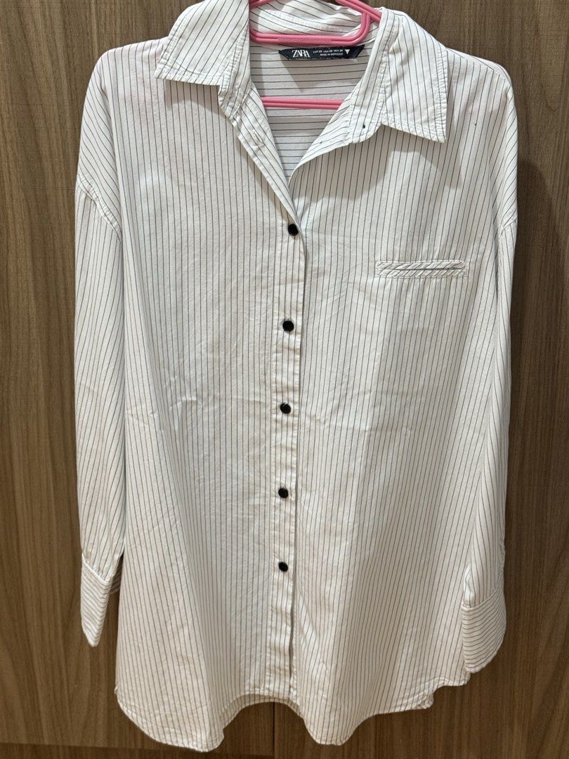 ZARA Striped Long Sleeve Shirt (Category: Longsleeves) located in Quezon City. Submitted by Cells_Collection (Listing ID 1444788075, Image 1). Description: - Classic white shirt with thin black pinstripes - Button-up front with a collar - Long sleeves with button cuffs - Relaxed fit for comfort - Versatile for casual or work outfits - Effortless to style.
