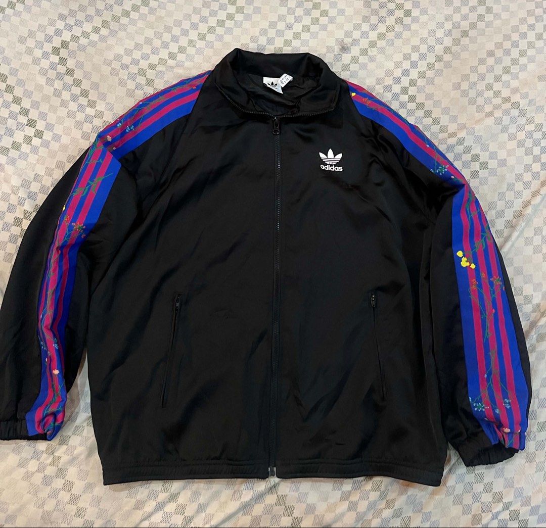 Adidas Track Jacket Black Blue Pink Stripes (Category: Coats, Jackets and Outerwear) located in Batangas. Submitted by gavsandrix (Listing ID 1441462080, Image 1). Description: - Classic Adidas track jacket - Black base with iconic three stripes on sleeves - Stripes feature blue and pink with a paint splatter effect - Full zip front closure - Convenient pockets - Perfect for casual wear or sports activities.
