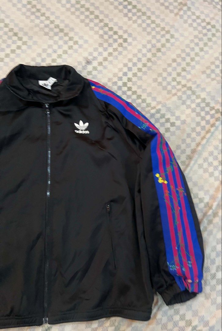 Adidas Track Jacket Black Blue Pink Stripes (Category: Coats, Jackets and Outerwear) located in Batangas. Submitted by gavsandrix (Listing ID 1441462080, Image 3). Description: - Classic Adidas track jacket - Black base with iconic three stripes on sleeves - Stripes feature blue and pink with a paint splatter effect - Full zip front closure - Convenient pockets - Perfect for casual wear or sports activities.
