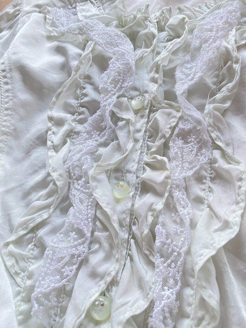 Blouse with Ruffles and Lace (Category: Blouses) located in Tarlac. Submitted by rieselects (Listing ID 1441465966, Image 3). Description: - Light long-sleeved blouse - Features ruffles and lace detailing down the front - Buttons and ties at the back for adjustable fit - L on tag, Fits S-M - Please note: faint stains on the left sleeve and holes, as shown in photos.