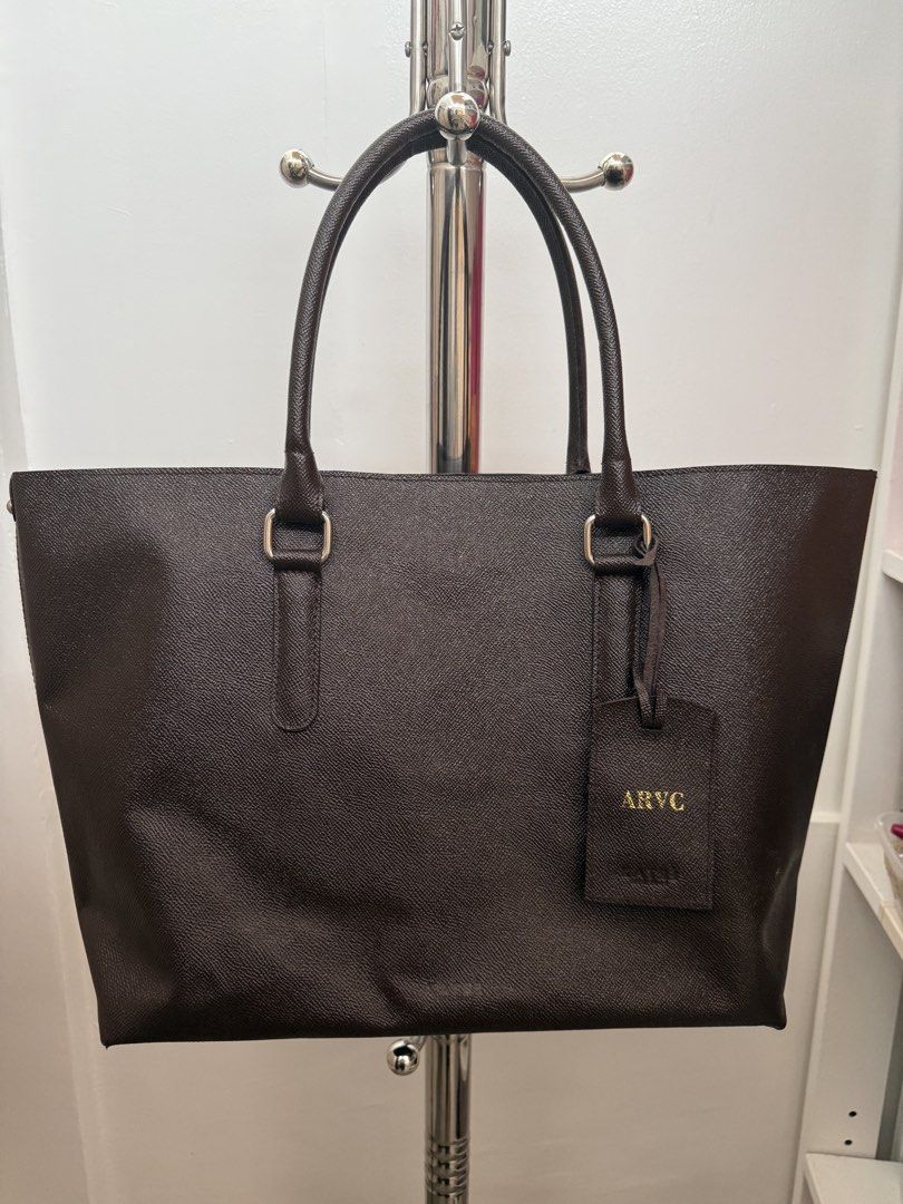 Dark Brown Textured Tote Bag with Pouch (Category: Tote Bags) located in Quezon City. Submitted by reivia.vend (Listing ID 1441426604, Image 1). Description: - Stylish dark brown textured tote bag - Includes a matching inner pouch with zipper closure - Two comfortable top handles - Attached luggage tag with initials 'ARVC' (removable) - Ideal for everyday errands or professional settings.
