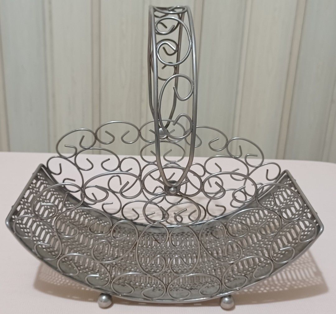 Decorative Metal Wire Basket with Handle (Category: Storage Boxes & Baskets) located in Quezon City. Submitted by wjmae (Listing ID 1441427182, Image 1). Description: - Decorative metal wire basket - Features an ornate handle - Intricate scrollwork along the sides - Woven pattern on the base - Stands on small ball feet - Ideal for holding fruit, flowers, or general organization - Adds a vintage aesthetic to any room.