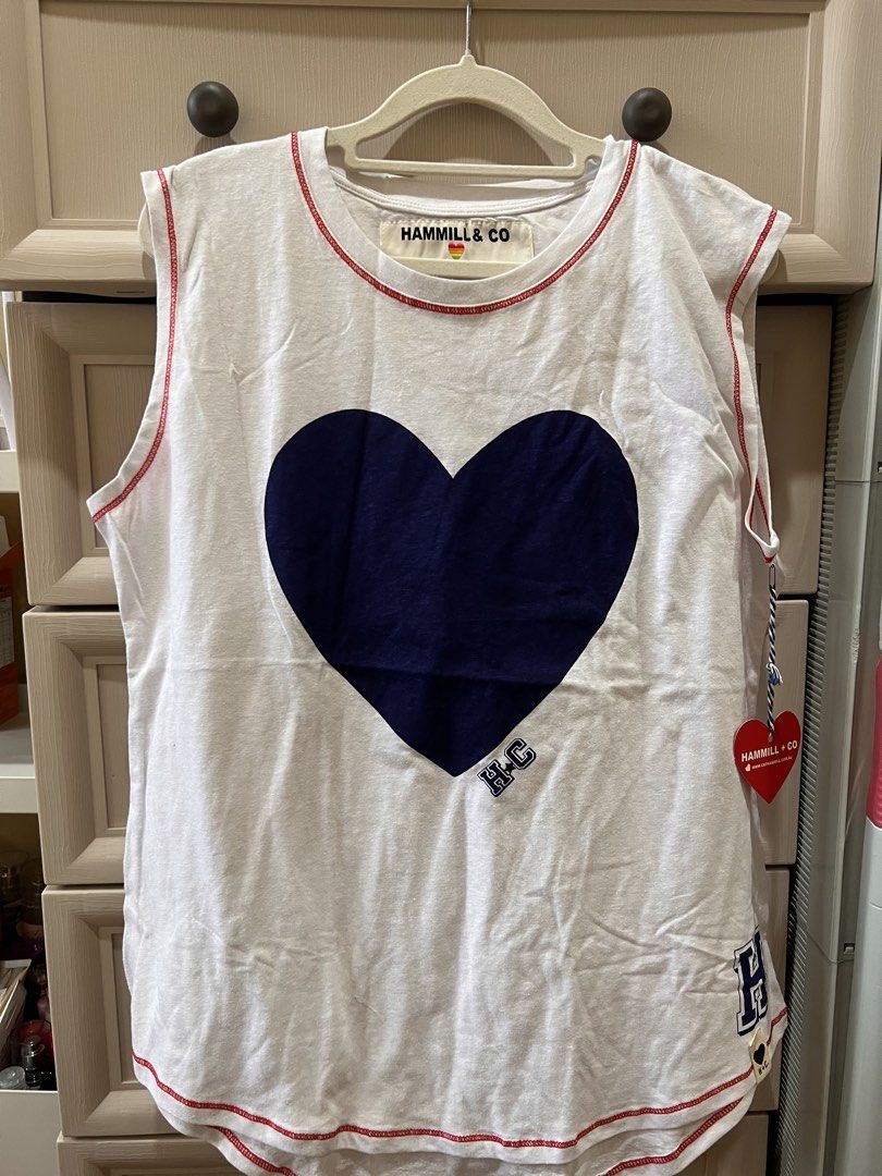 (Hammill & Co) White Heart Tank Top Size M (Category: Shirts) located in Angono. Submitted by elyenitty_ (Listing ID 1441501100, Image 1). Description: - White Hammill & Co tank top - Features a large navy blue heart graphic on the front - Red contrast stitching along the seams - Small 'H+C' logo detail on the hem - Super comfy and casual - Great for everyday wear.