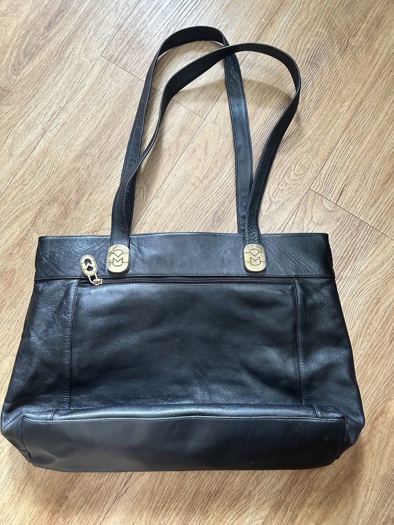 Marina D. Black Leather Tote Bag (Category: Tote Bags) located in Paranaque City. Submitted by charlottie72 (Listing ID 1441509399, Image 2). Description: - Classic black leather tote bag - Gold-tone hardware with Marina D. logo - Zippered top closure - Convenient exterior pocket - Interior lining features brand name - Spacious design for essentials - Ideal for everyday use or work.