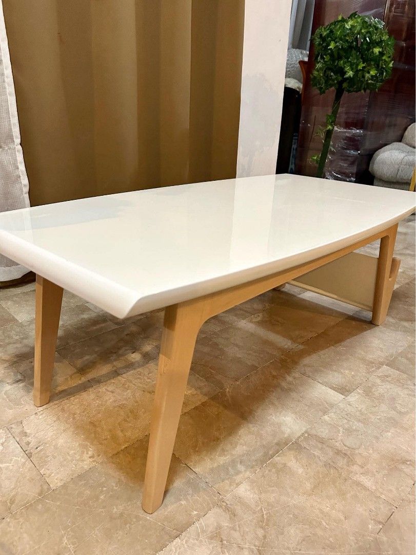 Modern White Center Table with Magazine Rack (Category: Tables & Sets) located in Bulacan. Submitted by nyesa21 (Listing ID 1441462626, Image 2). Description: - Modern white coffee table - Sturdy light wood legs - Convenient built-in magazine rack - Sleek, curved edges for a contemporary look - Easy-to-clean surface - Ideal size for living rooms and lounges - Perfect for everyday use.