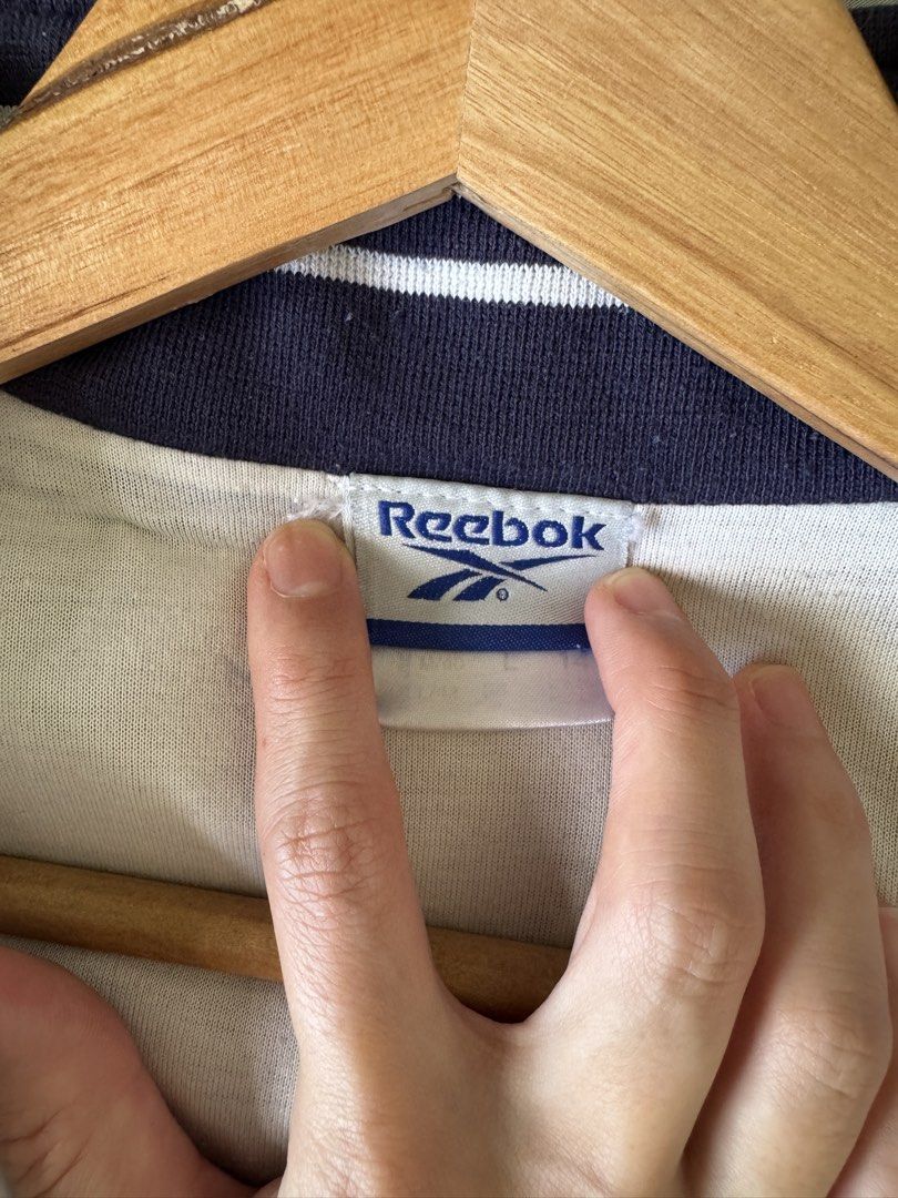 Reebok Track and Field Jacket (Category: Coats, Jackets and Outerwear) located in Singapore. Submitted by paperhandsss (Listing ID 1441405349, Image 2). Description: - Classic Reebok track jacket - Navy and white colorway - Stripes on sleeves - Full zip front - Stand-up collar - Two front pockets - Ideal for casual wear or sports.