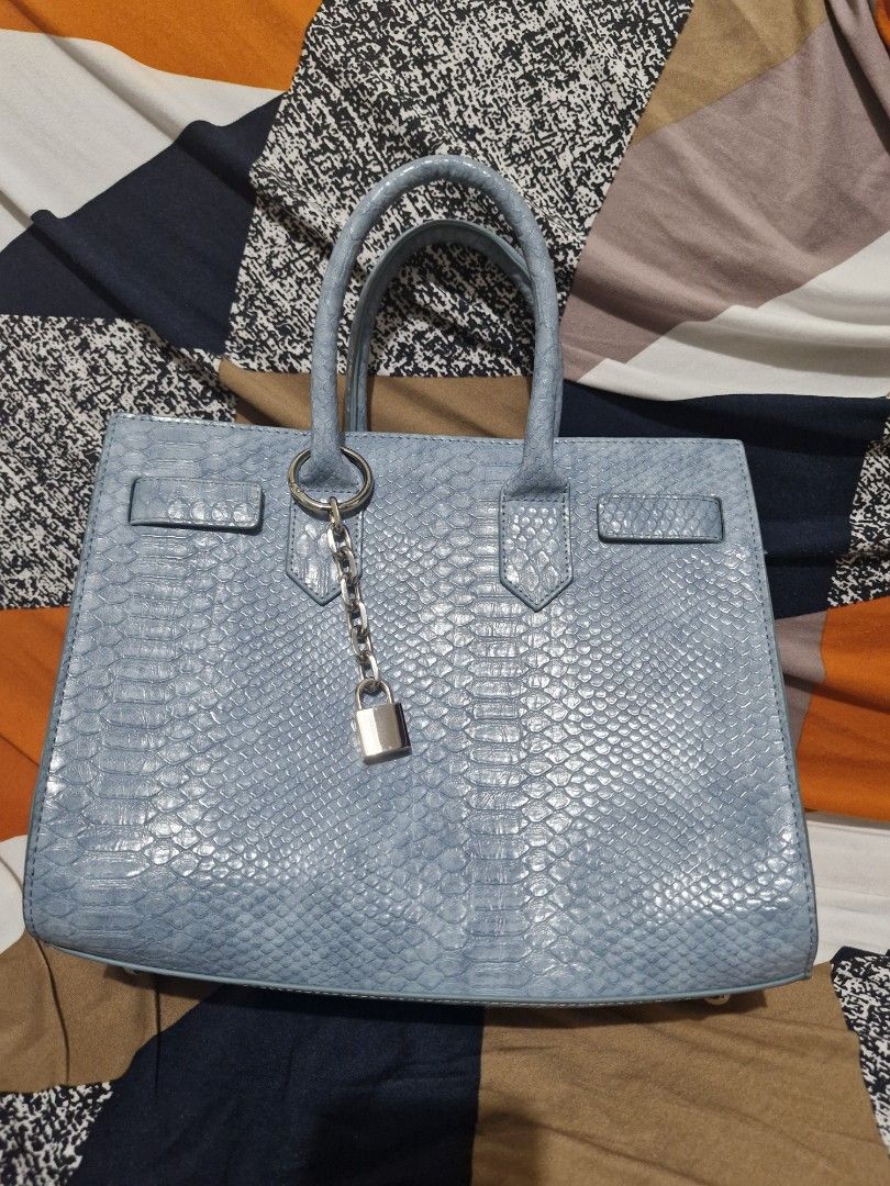 RICKI'S Light Blue Snakeskin Textured Handbag (Category: Tote Bags) located in Manila. Submitted by madam_q (Listing ID 1441420587, Image 1). Description: A gift lang din but di ako mahilig sa ganitong type ng bag.. - Light blue handbag with a stylish snakeskin texture. - Secure zip closure for your belongings. - Comfortable top handles for easy carrying. - Elegant silver hardware details. - Brand: RICKI'S - Ideal size for your daily essentials..
