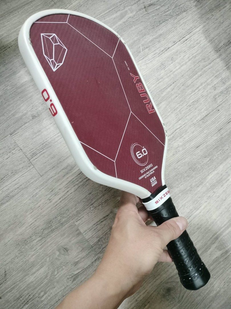 SIXZERO Ruby 6.0 Pickleball Paddle (14mm) (Category: Racket and Ball Sports) located in Quezon City. Submitted by teetharejade (Listing ID 1441472082, Image 2). Description: - SIXZERO Ruby 6.0 pickleball paddle - 14mm - Designed and engineered in the USA - Reliable performance for players - Distinctive maroon surface with geometric patterns - Textured black grip for enhanced handling - no issue to declare, marks seen on the corners are from the e