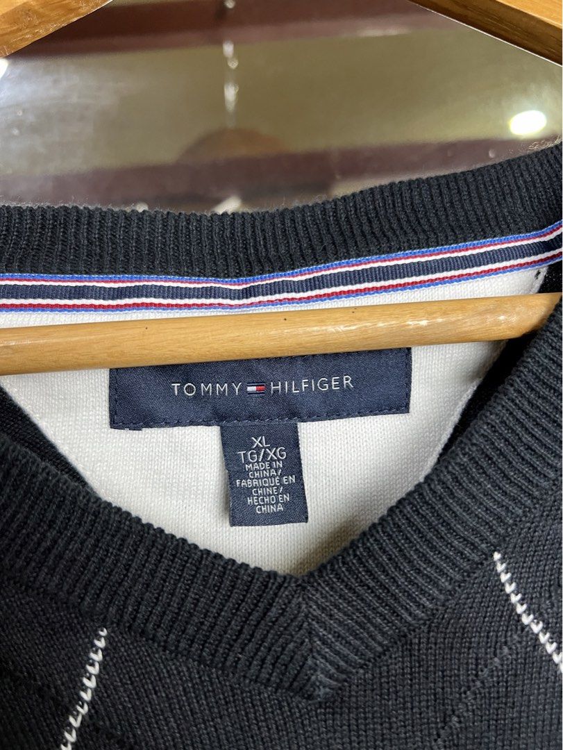 Tommy Hilfiger Black Argyle V-Neck Sweater (Category: Longsleeves) located in Iba. Submitted by saploot (Listing ID 1441539918, Image 3). Description: - Classic black Tommy Hilfiger sweater - 22x30 - Features a stylish white argyle pattern - V-neckline with ribbed cuffs and hem - Small Tommy Hilfiger flag logo on the chest - Comfortable knit material, great for layering or wearing solo.