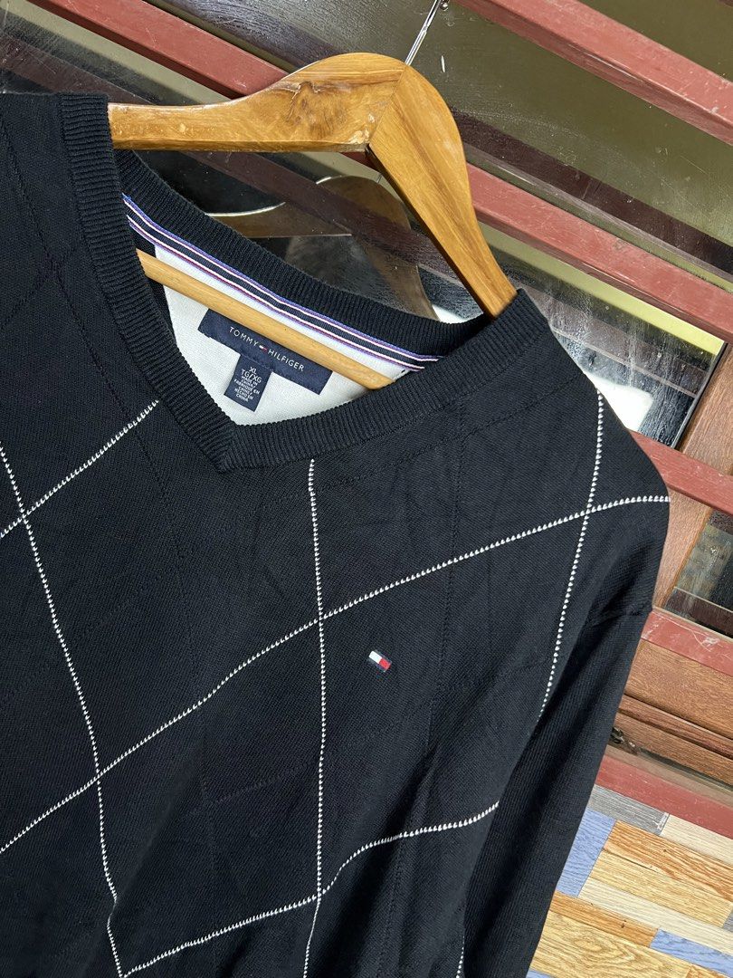 Tommy Hilfiger Black Argyle V-Neck Sweater (Category: Longsleeves) located in Iba. Submitted by saploot (Listing ID 1441539918, Image 2). Description: - Classic black Tommy Hilfiger sweater - 22x30 - Features a stylish white argyle pattern - V-neckline with ribbed cuffs and hem - Small Tommy Hilfiger flag logo on the chest - Comfortable knit material, great for layering or wearing solo.