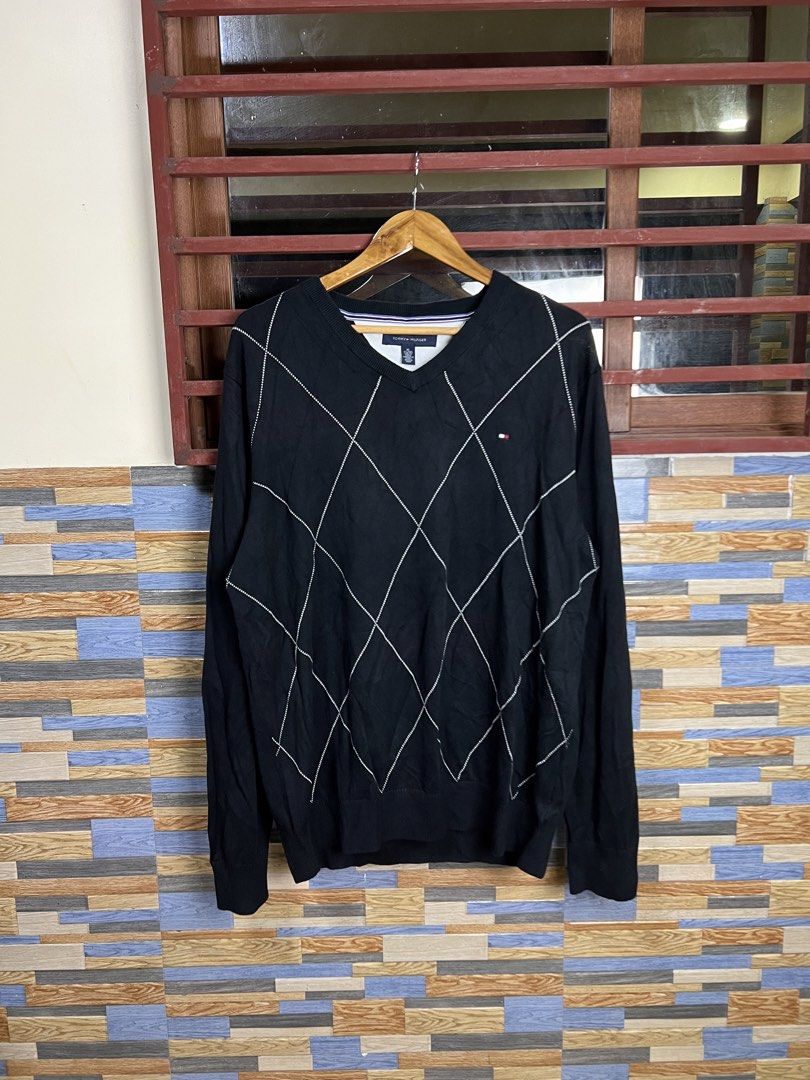 Tommy Hilfiger Black Argyle V-Neck Sweater (Category: Longsleeves) located in Iba. Submitted by saploot (Listing ID 1441539918, Image 1). Description: - Classic black Tommy Hilfiger sweater - 22x30 - Features a stylish white argyle pattern - V-neckline with ribbed cuffs and hem - Small Tommy Hilfiger flag logo on the chest - Comfortable knit material, great for layering or wearing solo.