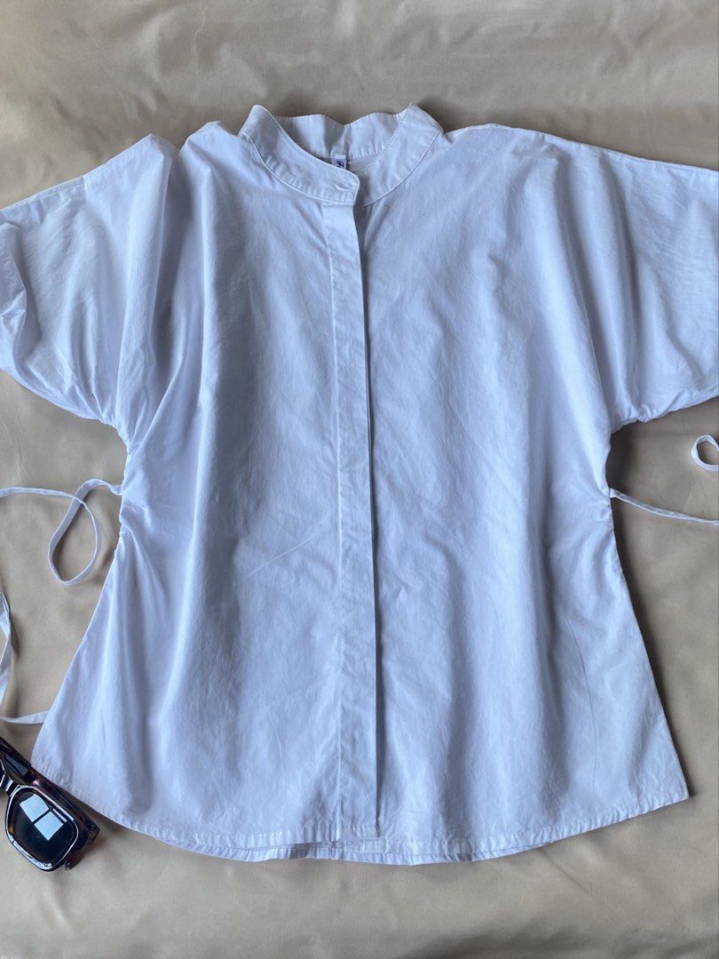 White Mandarin Collar Button Up Shirt with Tie Sides (Category: Blouses) located in Tarlac. Submitted by rieselects (Listing ID 1441464028, Image 1). Description: - Classic white shirt - Mandarin collar - Button-up front - Short, dolman-style sleeves - Adjustable side ties for a custom fit - Can be tied or untied - Simple and versatile.