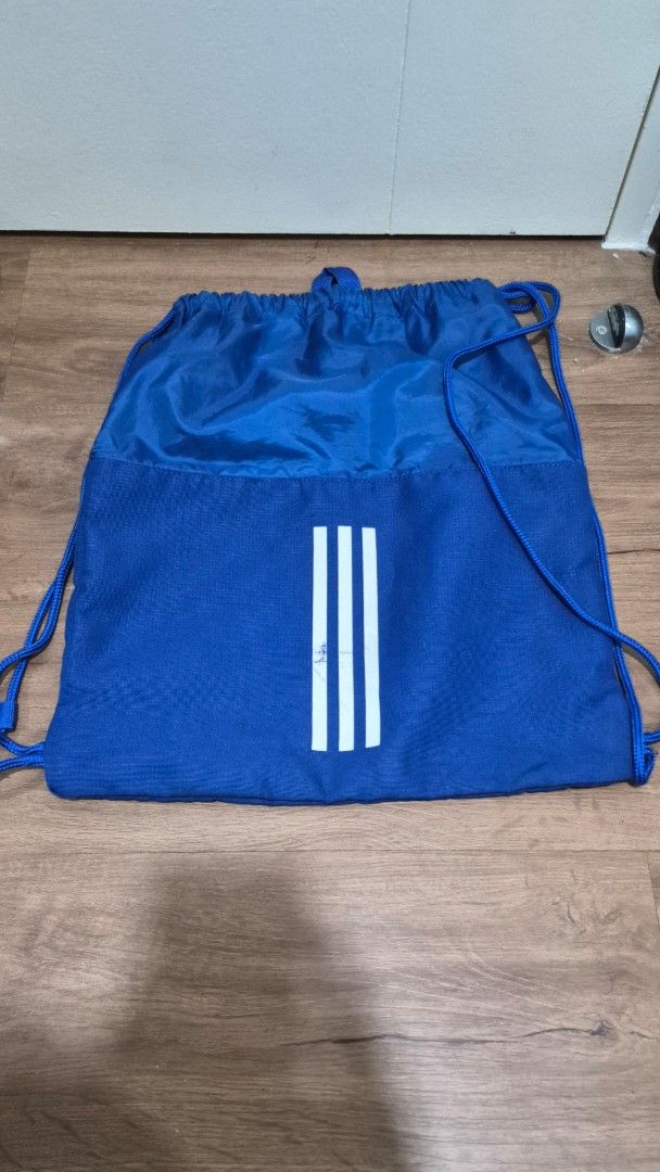 Adidas Blue Drawstring Bag (Category: Backpacks) located in Manila. Submitted by smgflurry_ (Listing ID 1445027721, Image 2). Description: - Classic blue Adidas drawstring bag - Iconic Adidas logo on the front - Signature three stripes detail on the back - Ideal for gym, sports, or everyday essentials - Lightweight and easy to carry.