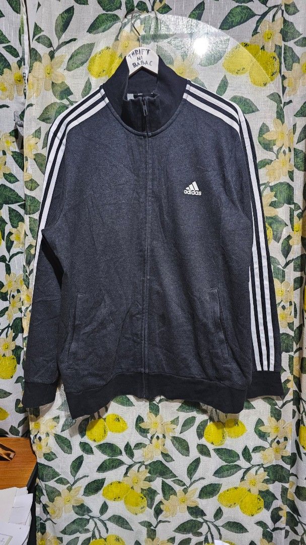 Adidas Track Jacket with 3 Stripes (Category: Coats, Jackets and Outerwear) located in Kibawe. Submitted by Thrift_ni_Babac (Listing ID 1445023622, Image 1). Description: - Classic Adidas track jacket - Color: Dark grey with white 3 stripes on sleeves - Full zip closure - Minor stain on front (visible in last photo) - Perfect for casual wear or sports activities - Dimes: 22 x 29.