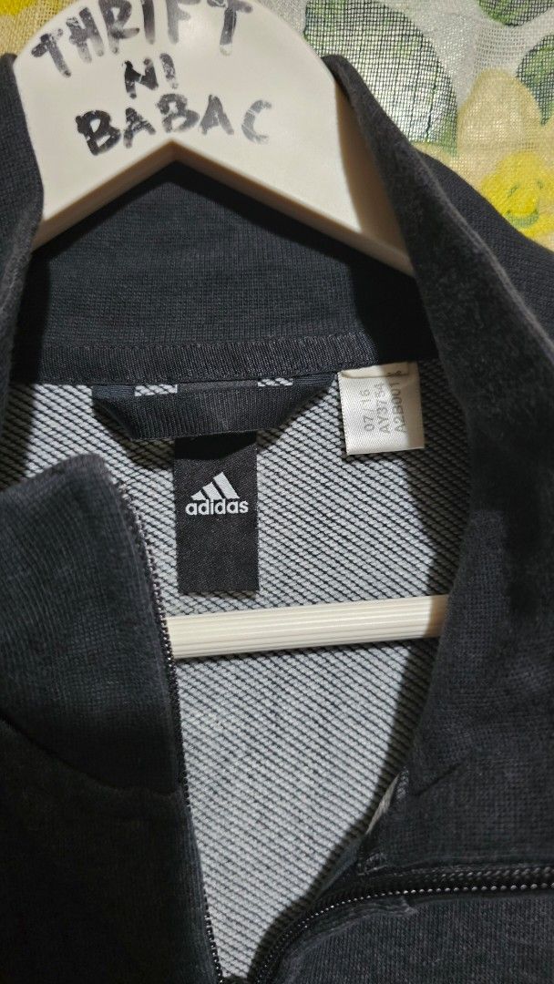 Adidas Track Jacket with 3 Stripes (Category: Coats, Jackets and Outerwear) located in Kibawe. Submitted by Thrift_ni_Babac (Listing ID 1445023622, Image 2). Description: - Classic Adidas track jacket - Color: Dark grey with white 3 stripes on sleeves - Full zip closure - Minor stain on front (visible in last photo) - Perfect for casual wear or sports activities - Dimes: 22 x 29.