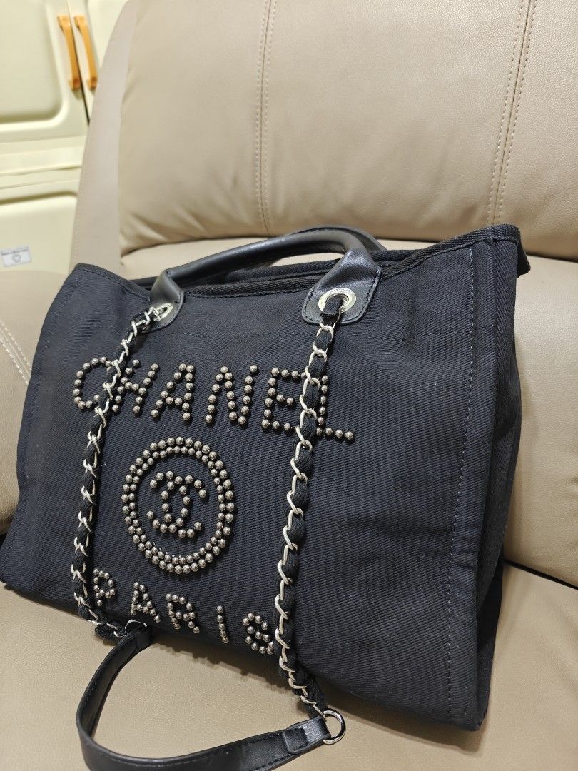 Chanel Black Canvas Studded Tote Bag (Category: Luxury Bags & Wallets) located in Pililla. Submitted by reginedomasig (Listing ID 1444919227, Image 2). Description: - Chanel black canvas tote bag - Embellished with stud details on the brand name and logo - Comfortable leather handles and stylish chain straps - Multiple interior compartments for organization - Ideal for everyday use and errands.