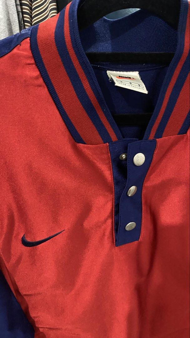 Nike Baseball Jacket Red Blue Snap Button (Category: Coats, Jackets and Outerwear) located in Porac. Submitted by moethrifter (Listing ID 1444949615, Image 2). Description: - Vintage Nike Jacket - Color: Red and Navy Blue - Size: L - Short sleeves - Snap button closure at the neck - Striped detailing on the collar - Nike swoosh logo on the chest - Perfect for collectors.