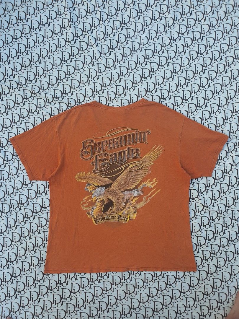 Orange Harley Davidson T-Shirt with Eagle Graphic (Category: Tshirts & Polo Shirts ) located in San Fernando. Submitted by retro.district. (Listing ID 1445025193, Image 1). Description: - Orange Harley Davidson T-Shirt - Features a large eagle graphic with flames and 'Performance Parts' text - Classic Harley Davidson logo on the front chest - Made from comfortable cotton material - Perfect for any Harley Davidson fan - Ready for its new owner.