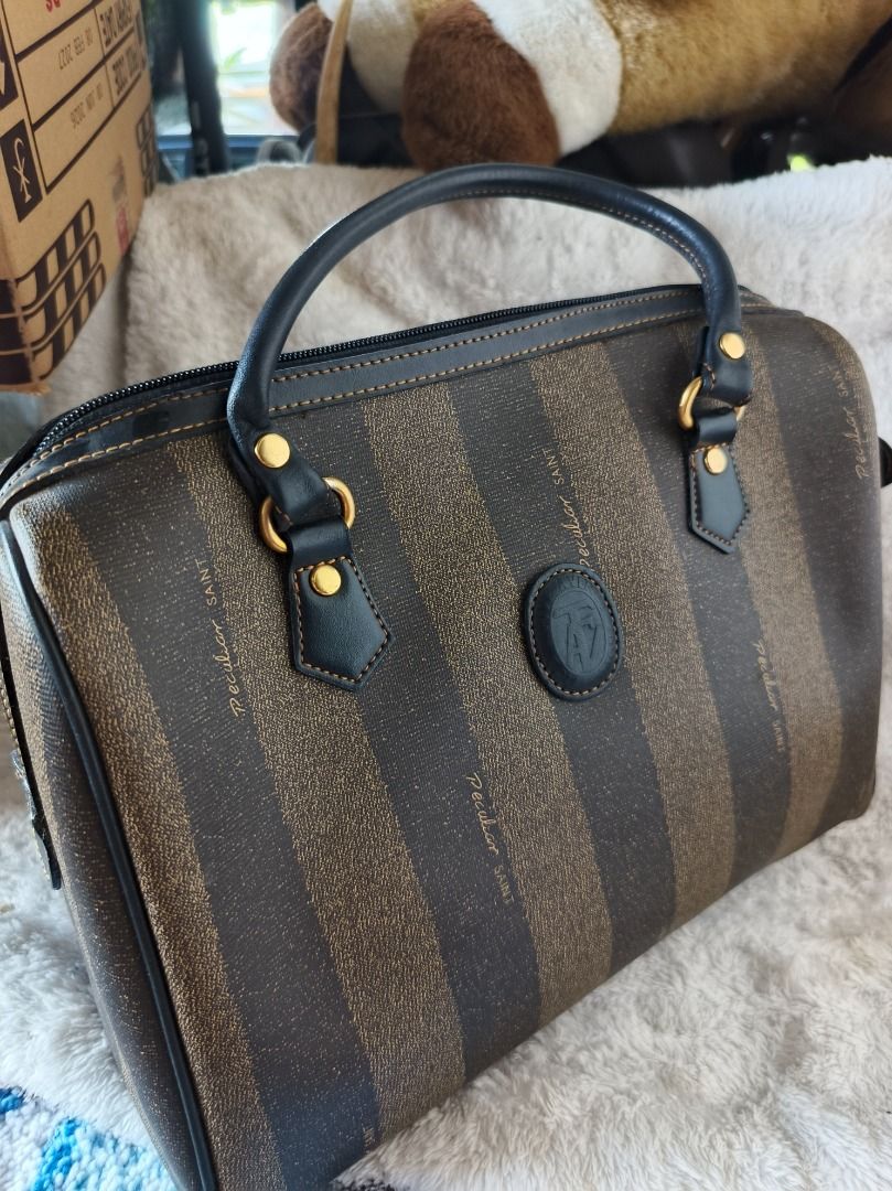 Peculiar Saint Pattern Boston Bag (Category: Luxury Bags & Wallets) located in San Leonardo. Submitted by burgossanleonardo.12345 (Listing ID 1444886218, Image 2). Description: - Classic Fendi Zucca pattern Boston bag - Brown and black striped design - Genuine leather trim and handles - Secure top zipper closure - Convenient front pocket - Interior zippered pocket - Timeless and versatile for everyday use.