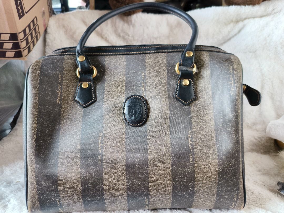 Peculiar Saint Pattern Boston Bag (Category: Luxury Bags & Wallets) located in San Leonardo. Submitted by burgossanleonardo.12345 (Listing ID 1444886218, Image 1). Description: - Classic Fendi Zucca pattern Boston bag - Brown and black striped design - Genuine leather trim and handles - Secure top zipper closure - Convenient front pocket - Interior zippered pocket - Timeless and versatile for everyday use.