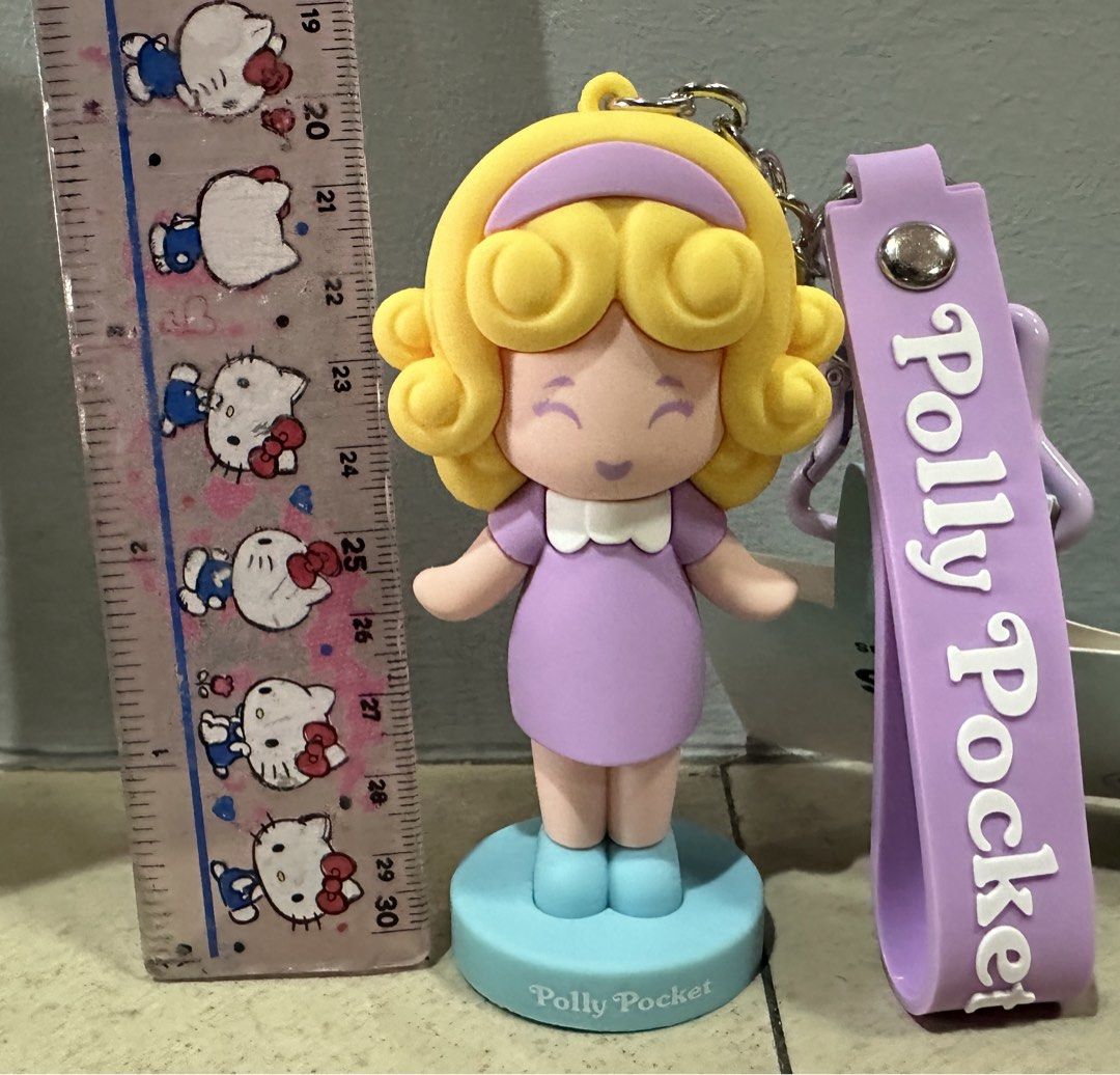 Polly Pocket Keychain Figure with Strap (Category: Kids Toys) located in Caloocan City. Submitted by ashleyscorner (Listing ID 1444868411, Image 2). Description: - Adorable Polly Pocket keychain figure. - Features a purple strap with 'Polly Pocket' text. - Figure stands on a small blue base. - Ideal for attaching to bags or keys. - A must-have collectible for Polly Pocket enthusiasts..
