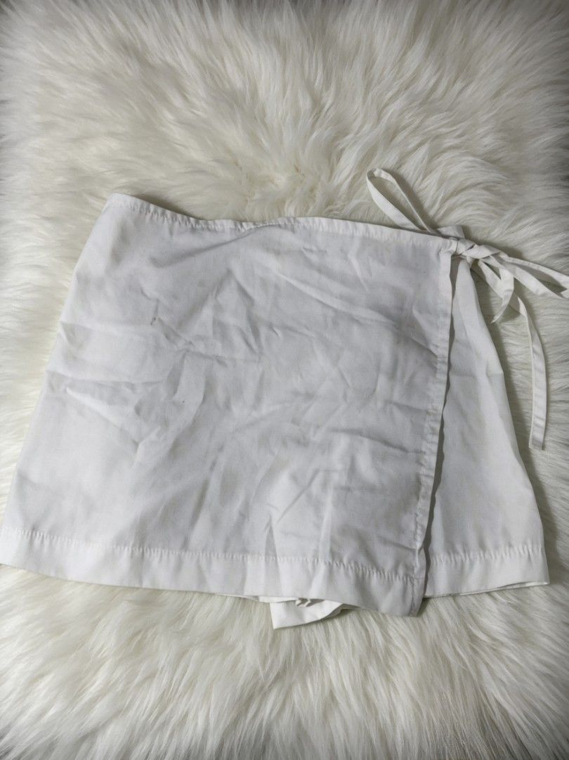 White Wrap Skirt with Tie Detail (Category: Skirts) located in Quezon City. Submitted by mayyang_28 (Listing ID 1444967347, Image 1). Description: - White wrap skirt - Mini skirt style - Adjustable tie closure on the side - Made of plain white cotton fabric - Versatile for casual wear or as a beach cover-up.
