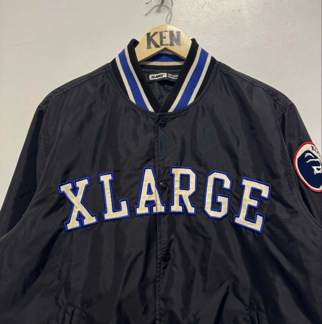XLARGE Black Varsity Jacket with Blue and White Stripes (Category: Coats, Jackets and Outerwear) located in Manila. Submitted by esparciake75752 (Listing ID 1444893018, Image 2). Description: - Cool XLARGE varsity jacket - Black with blue and white striped collar and cuffs - Features the XLARGE logo across the chest - Circular patch on the left sleeve - Button-up front - Quilted lining inside - Great for casual wear.