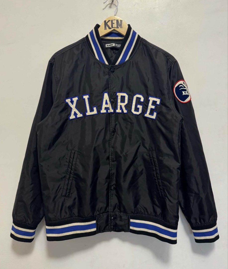 XLARGE Black Varsity Jacket with Blue and White Stripes (Category: Coats, Jackets and Outerwear) located in Manila. Submitted by esparciake75752 (Listing ID 1444893018, Image 1). Description: - Cool XLARGE varsity jacket - Black with blue and white striped collar and cuffs - Features the XLARGE logo across the chest - Circular patch on the left sleeve - Button-up front - Quilted lining inside - Great for casual wear.