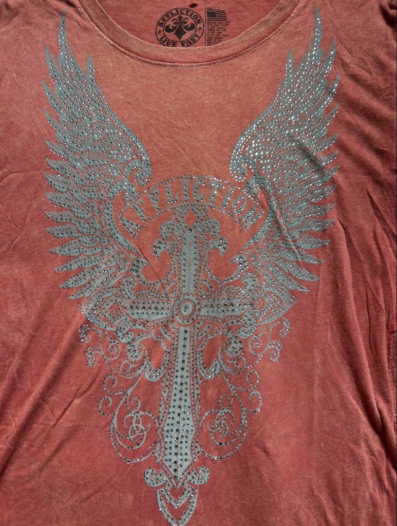 Affliction Live Fast Wings Cross Graphic Tee Shirt (Category: Tshirts & Polo Shirts ) located in Santa Ana. Submitted by 999h03 (Listing ID 1445210256, Image 3). Description: - Affliction T-Shirt - Size: Small on tag, s-l - Graphic Design: Wings, cross, 'Live Fast' - Features: Lace-up sides with ties - Fabric: Distressed look.