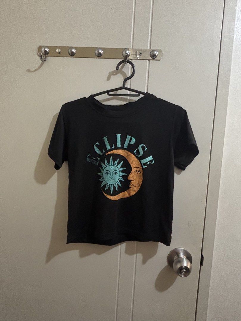 Black Crop Top Eclipse Sun and Moon Graphic T-shirt (Category: Tshirts & Polo Shirts ) located in Manila. Submitted by declutterrinmanila (Listing ID 1445144072, Image 1). Description: - Cool black crop top - Features an eclipse graphic with sun and moon design - 'Eclipse' text across the top - Short sleeves - Crew neck - Perfect for casual wear 🩷 Price negotiable Sf should be shouldered by buyer.