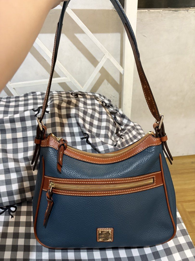 Original Dooney & Bourke Pebble Grain Leather Shoulder Bag (Category: Luxury Bags & Wallets) located in Manila. Submitted by cooltree-5297 (Listing ID 1445220568, Image 2). Description: - Blue pebble grain leather with tan leather trim - Zip top closure - Front zip pocket - Gold tone hardware - Adjustable shoulder strap - Interior pockets - Spacious and ideal for everyday use.