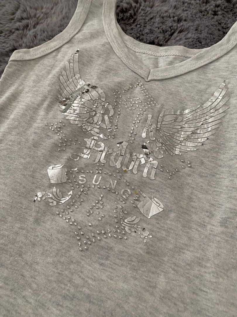 Grey Tank Top with Rhinestone Wings Graphic (Category: Sleeveless) located in Angeles City. Submitted by annrinaaa (Listing ID 1445112627, Image 2). Description: - Grey V-neck tank top - Features a cool rhinestone graphic with wings and text - Sparkly details all over the front - Sleeveless design - Great for casual wear or layering.