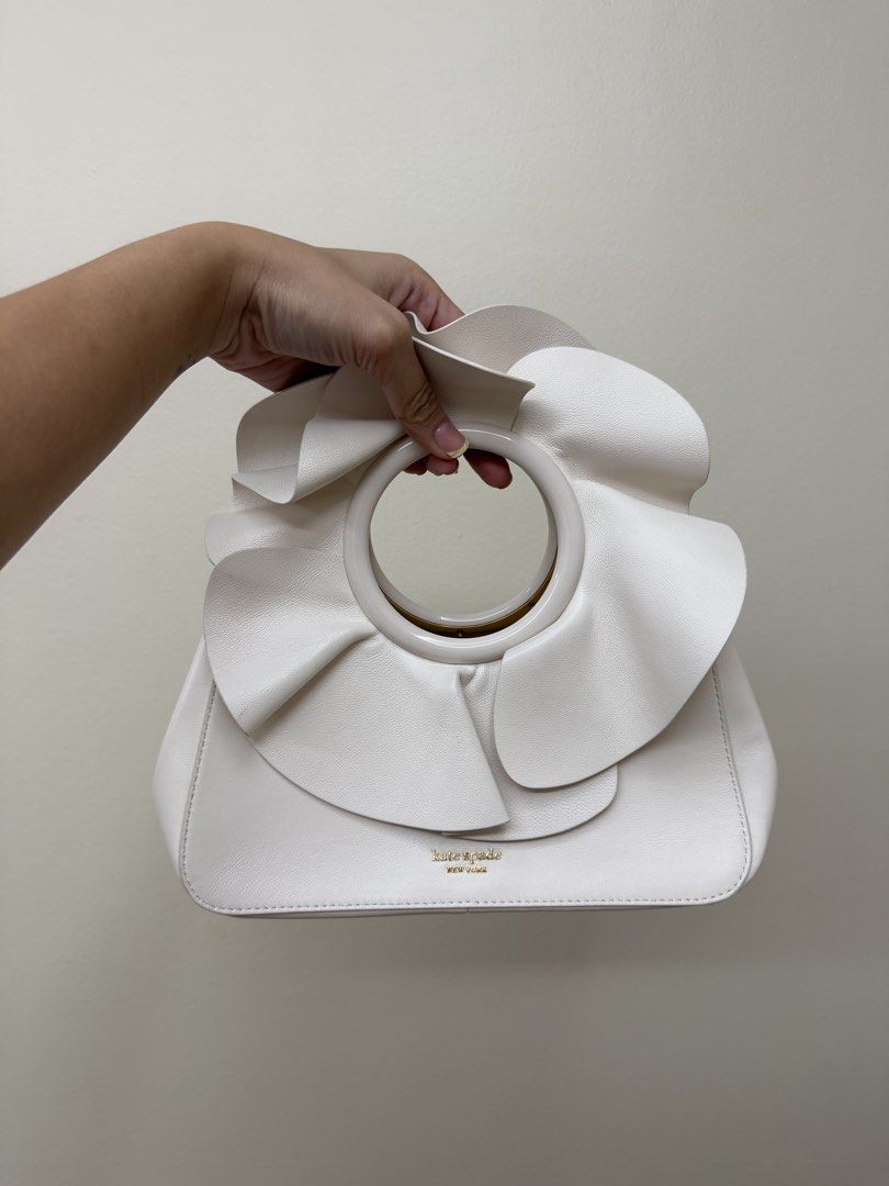 Kate Spade Flora Bracelet (Category: Luxury Bags & Wallets) located in Manila. Submitted by tashvintagefinds (Listing ID 1445194847, Image 1). Description: - Kate Spade Flora Bracelet Bag - Condition is very nice and like new - Nice white color - With strap - Only flaw: the petal on the handle is a bit folded - Negotiable.