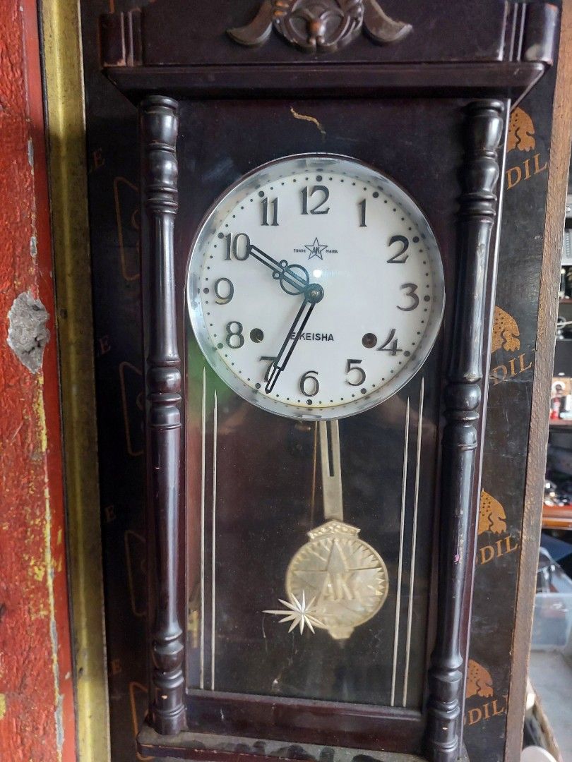 Keisha Wooden Mantel Clock with Pendulum (Category: Clocks) located in Quezon City. Submitted by jpnvintageonline (Listing ID 1445139704, Image 1). Description: - Vintage Keisha mantel clock - Dark wood casing with decorative carvings - White face with black Roman numerals - Features a swinging pendulum - Includes winding key - Perfect for display or as a functional timepiece - Adds a classic touch to any room.