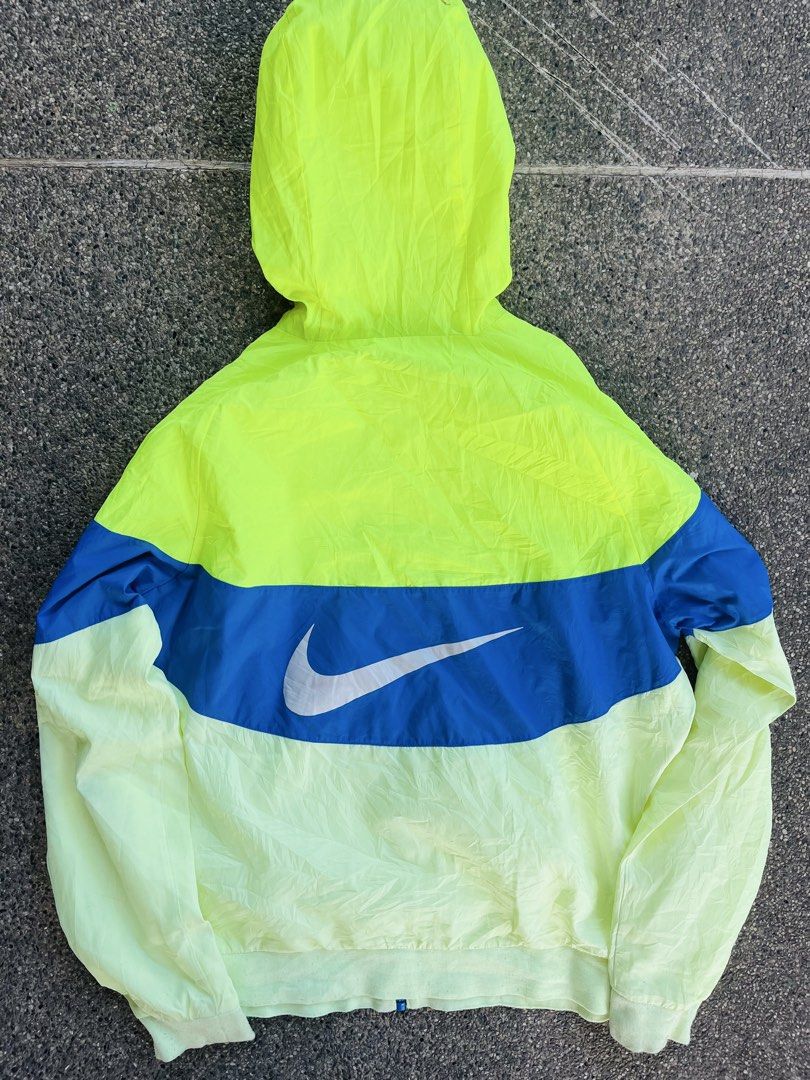 Nike Windbreaker Jacket Neon Yellow Blue (Category: Coats, Jackets and Outerwear) located in Manila. Submitted by jaspermack50866 (Listing ID 1445065976, Image 2). Description: - Bright neon yellow Nike windbreaker jacket - Features a striking blue chevron design - Nike logo on the front - Large swoosh graphic on the back - Hooded style for added versatility - Lightweight material, ideal for outdoor activities or casual wear.