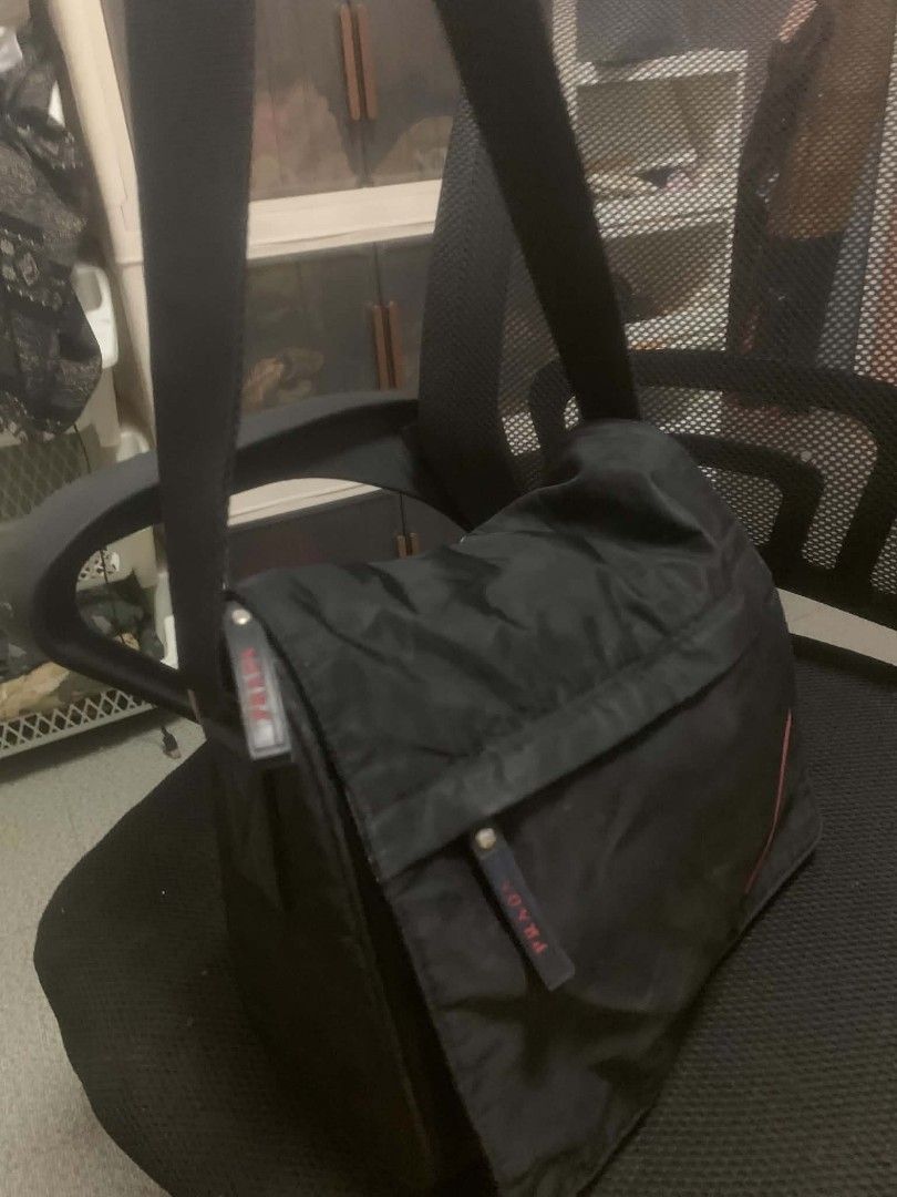 Prada Black Nylon Crossbody Bag (Category: Luxury Bags & Wallets) located in Quezon City. Submitted by ukaybag.ph09 (Listing ID 1445052674, Image 3). Description: - Prada crossbody bag - Durable nylon material - Front pocket with signature red Prada logo - Adjustable strap with metal buckle - Secure zipper closure - Minor marks on front (please check photos for details) - Ideal for everyday wear.