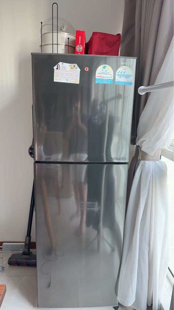 Sharp Refrigerator (Category: Refrigerators & Freezers) located in Singapore. Submitted by ailingmiao.618 (Listing ID 1445101271, Image 1). Description: - Sharp refrigerator for sale - Sleek silver exterior - Ideal size for small households - Stickers on front (likely removable) - Working condition - Includes vacuum cleaner.