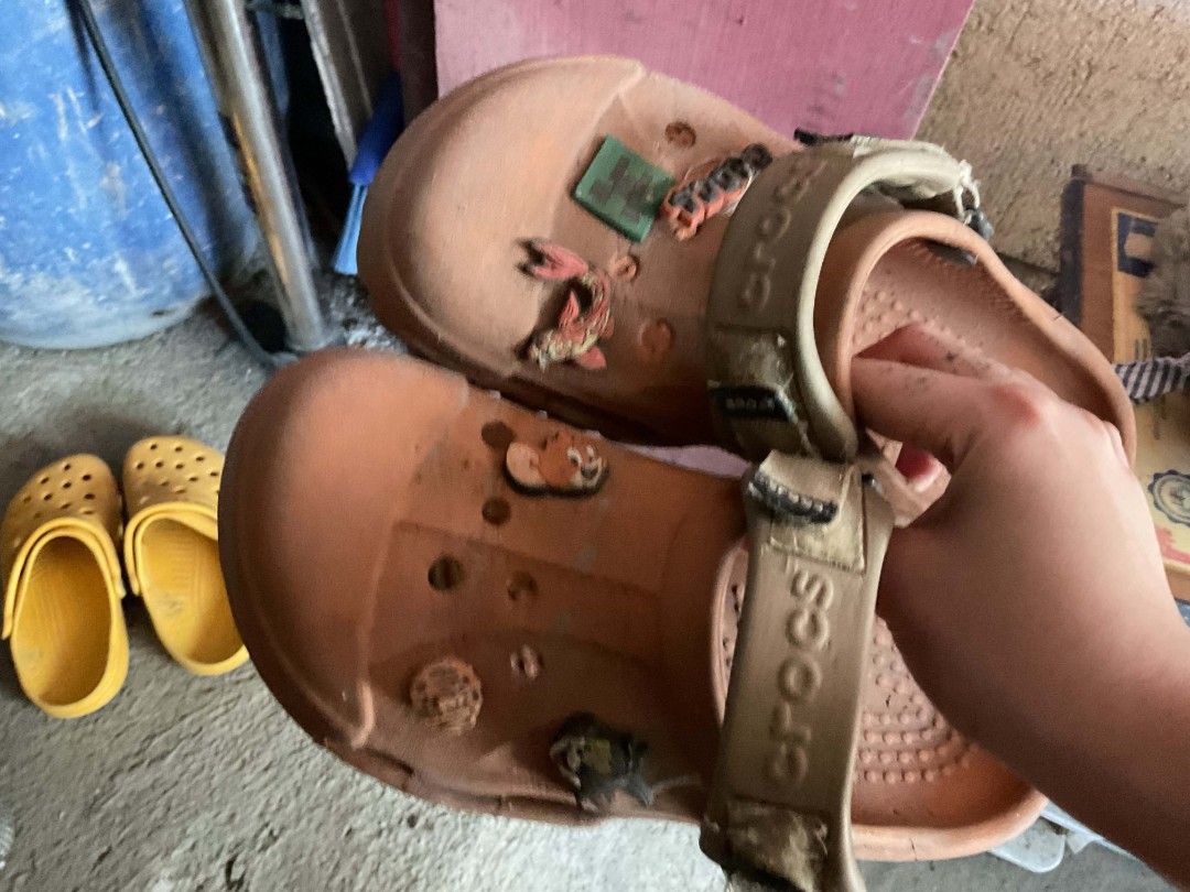 TAKE ALL Crocs Clogs with Jibbitz Charms (Category: Slippers and slides) located in Manila. Submitted by declutterthisandthat (Listing ID 1445061197, Image 2). Description: - Bundle includes two pairs of used Crocs clogs. - One pair is brown and features Jibbitz charms. - The brown pair's strap has the Crocs logo. - The second pair is yellow. - Both pairs are sold as a set. !!! need lang i wash ng water marumi lang sa pic!!!! isang classic orange