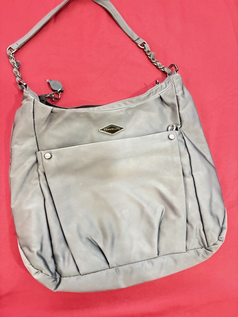 Travelon Grey Nylon Shoulder Bag with Adjustable Strap (Category: Shoulder Bags) located in Los Banos. Submitted by tripleceedoubletwo (Listing ID 1445076778, Image 3). Description: - Grey Travelon shoulder bag - Durable nylon material - Front pocket with snap closure - Zippered back pocket - Interior shows some stains - Detachable and adjustable shoulder strap - Perfect for everyday use or travel - Dimensions: 13 x 3 x 11 inches - MOP: Gcash or 