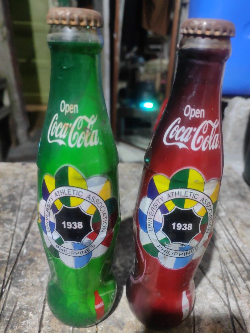 Coca-Cola Bottles - University Athletic Association 1938 (Category: Vintage Collectibles) located in Manila. Submitted by richardestano (Listing ID 1445346687, Image 2). Description: - Set of 2 Coca-Cola bottles (1 red, 1 green) - Features University Athletic Association 1938 design - Ideal for collectors - Caps show some rust.