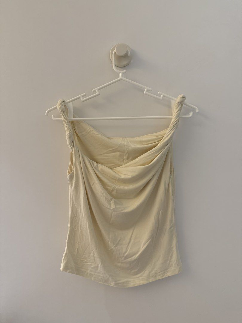 Cream Cowl Neck Twisted Strap Tank Top (Category: Sleeveless) located in Manila. Submitted by chen.854 (Listing ID 1445381091, Image 1). Description: - Cream colored tank top - Features a cowl neckline - Twisted straps at the shoulders - Sleeveless design - Made from a soft, stretchy material - Versatile for layering or wearing on its own - Simple and chic style.