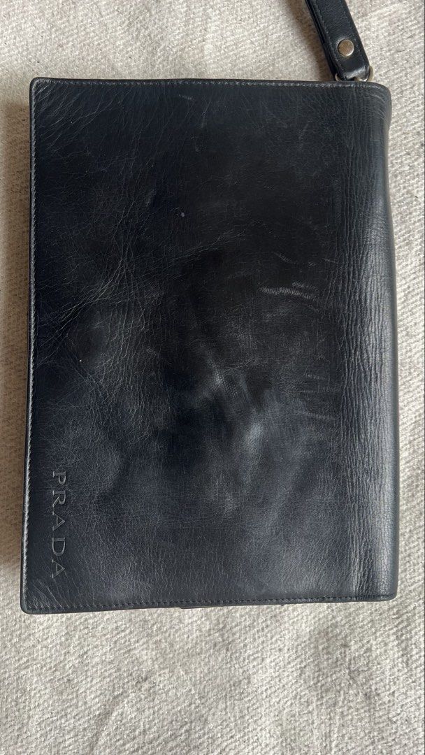 Prada Black Leather Wristlet Clutch Bag (Category: Luxury Bags & Wallets) located in Cagayan de Oro. Submitted by nelsondel21723 (Listing ID 1445327250, Image 2). Description: - Authentic Prada black leather clutch - Features a detachable wrist strap - Leather shows minor signs of wear (scuffs, creases) - Classic embossed Prada logo on the front - Perfect for carrying your essentials.