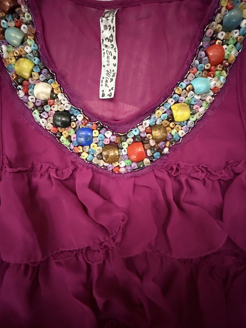 Purple Ruffled Tank Top with Beaded Neckline (Category: Sleeveless) located in Malinao. Submitted by mishmash2026 (Listing ID 1445374663, Image 3). Description: - Adorable purple tank top - Features charming ruffles all over - 16inches x 23.5inches - Neckline adorned with colorful beads - Sleeveless design for comfort - Versatile for casual day or night out - Easily pairs with jeans or skirts.