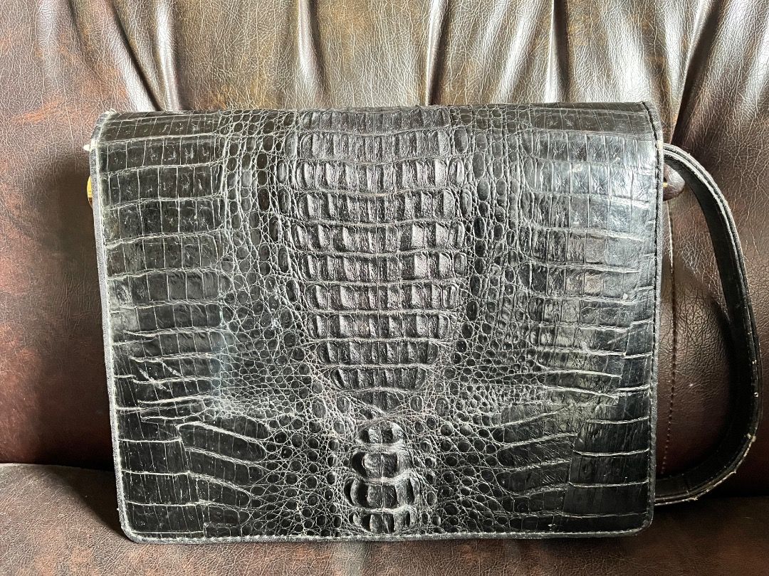Black Crocodile Handbag with Gold Clasp (Category: Luxury Bags & Wallets) located in Makati City. Submitted by Ina_Ndang (Listing ID 1445584263, Image 2). Description: - Genuine black crocodile skin clutch - Features a secure gold-tone clasp closure - Adjustable strap for comfortable wear - Multiple compartments inside for organized storage - Shows slight signs of wear on edges and hardware, adding character - A classic and versatile piece for an