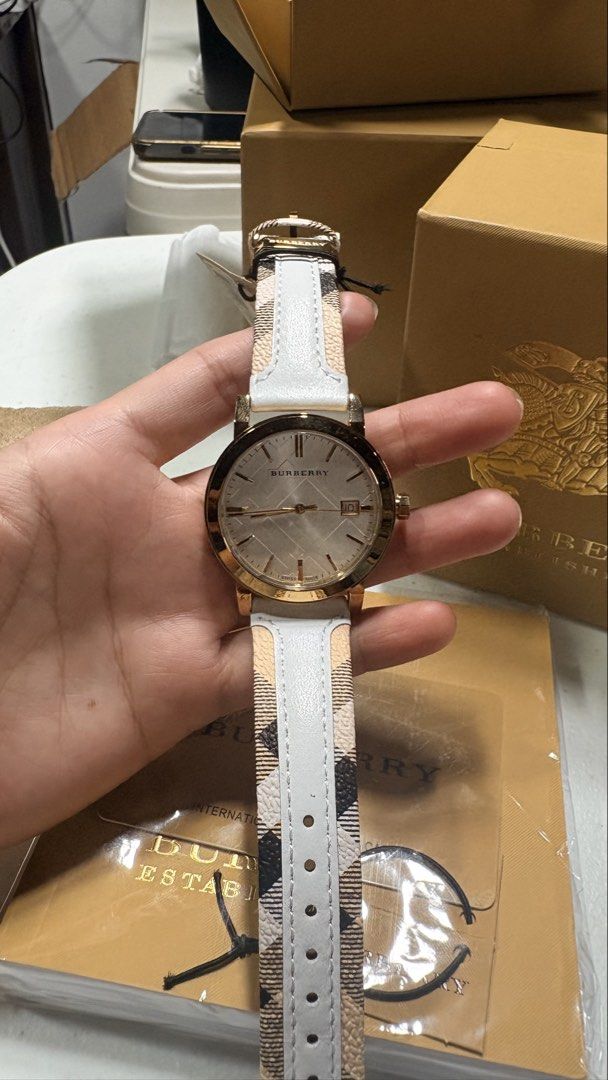 Burberry Watch (Category: Women's Watches) located in Angeles City. Submitted by sum49 (Listing ID 1445550126, Image 3). Description: BRAND: Burberry MODEL NUMBER: BU9015 CASE WIDTH: 38mm CASE COLOUR: Gold CASE MATERIAL: Stainless Steel CASE SHAPE: Circular MOVEMENT: Quartz (Battery) DIAL COLOUR: Silver STRAP MATERIAL: Leather STRAP COLOUR: White CLASP TYPE: Buckle CRYSTAL: Sapphire WATER RESISTANCE: 50 Metres - More Info PACKAGING: Official Burb